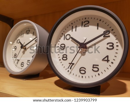 Beautiful Black and Grey Modern clock with Round shape has black hour hand and black minute hand and Interior decorate backdrop and the number of the clock is displayed in black lines