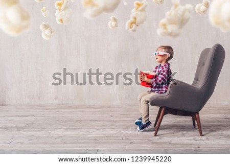 Surprised little spectator with popcorn at home