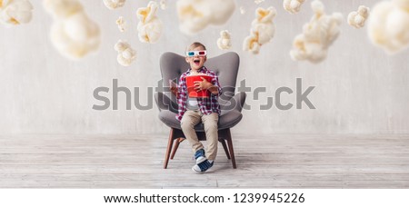 Surprised kid with popcorn in 3d glasses in the cinema