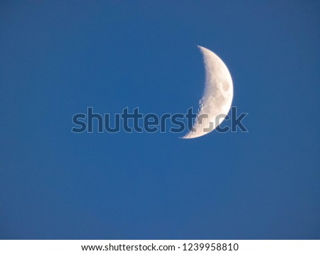 young moon clear on light blue sky, harvest half moon, crater 