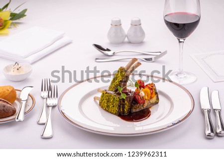 Giving of a hot dish at restaurant, rack of lamb with the fried vegetables in berry sauce