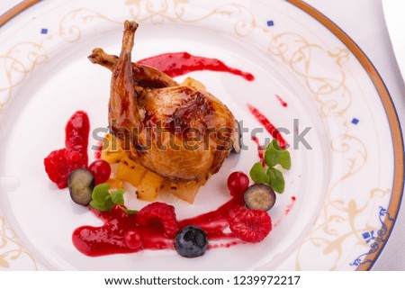 A fried quail with berry sauce and fresh berries