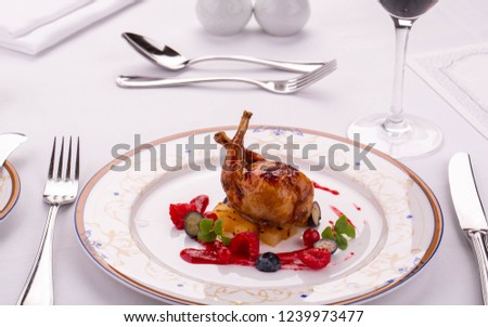 The quail fried on a grill is served on a pillow from pineapples with berry sauce and berries