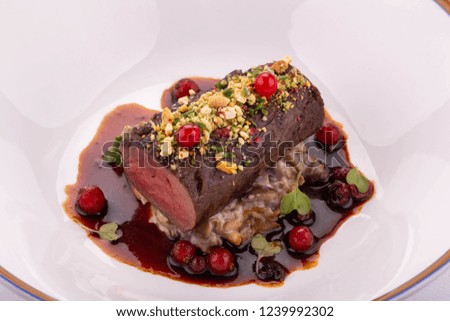 A stake from beef on a mushroom pillow with berry sauce and greens