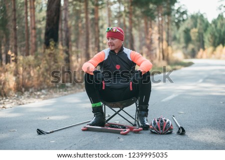 Training an athlete on the roller skaters. Biathlon ride on the roller skis with ski poles, in the helmet. Autumn workout. Roller sport. Adult man riding on skates. Athlete is getting ready to start.