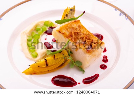 A halibut on a grill with caramelized onions and berry sauce