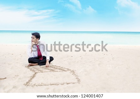 Young businessman is thinking something while sitting on a beach