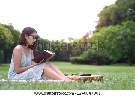Beautiful young woman writing on notebook in the park