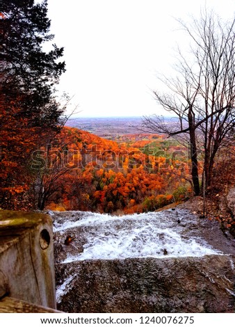 Beautiful fall picture of a waterfall and orange leaves background.