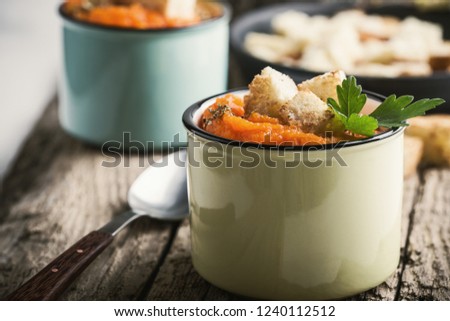 Autumn pumpkin soup served on wooden table in rural mugs, healthy vegan meal, plant based meal