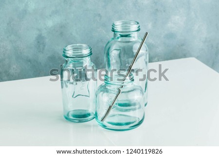empty glass recycled bottles for breakfast, fresh juice and other kitchen needs. glassware on white table and blue background