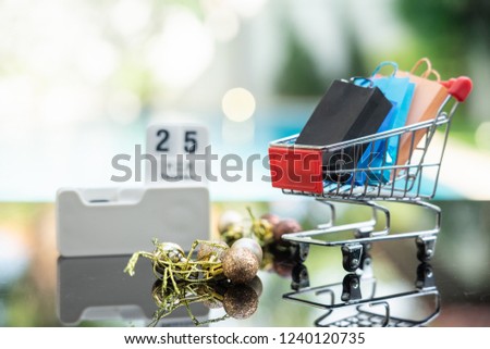 Shopping bags in shopping cart and calendar on date 25 December isolated on white background. Concept of Black Friday, boxing day, year end sales.
