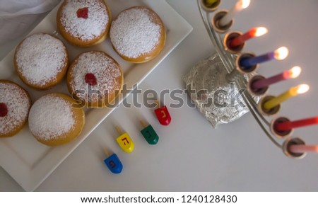 Top view of Jewish holiday Hanukkah symbols against white background; traditional spinning top, menorah (traditional candelabra), Donuts  with jam and candles. Background.Copy space. isolated.