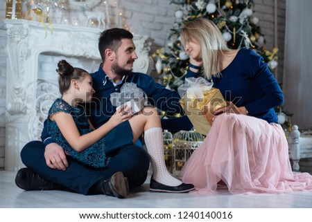 Christmas photo of happy family with gift boxes on background of decorated Christmas tree. Family celebrates New year