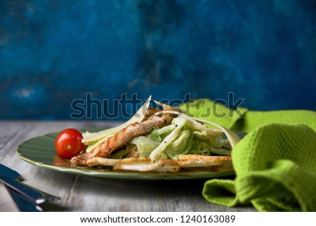 Fresh caesar salad in a green plate on a light wooden table pic
