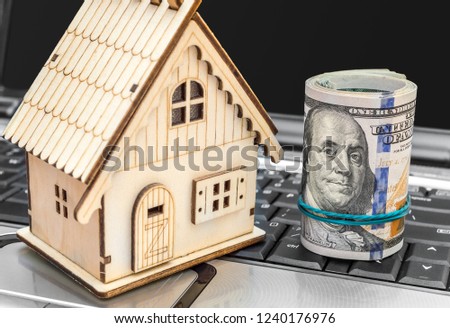 Model of house with rolled money on laptop keyboard. Close up.