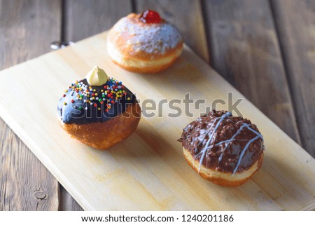 Close up view of tasty various donuts on wood background. Hanukkah celebration concept. Round jelly or jam doughnut sufganiyot and chocolate sufganiyah for Chanukah Jewish holiday.