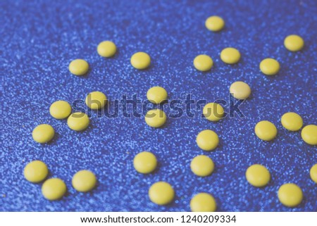 Small yellow orange beautiful medical pharmaceptic round pills, vitamins, drugs, antibiotics on a blue background, texture. Concept: medicine, health care. Flat lay, top view.