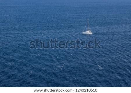 summer holidays concept of sea waves surface and small white yacht from above aerial shot, copy space 