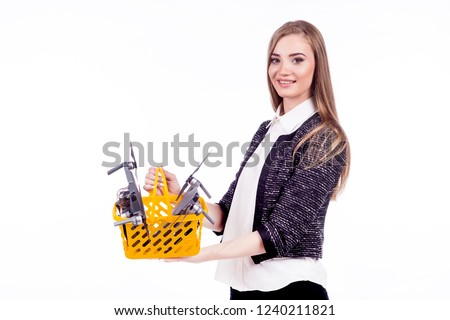 Beautiful girl holding a flying drone. Flying drones are in the shopping basket. On a white background. Theme selling and buying drone
