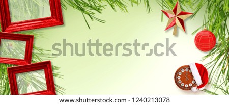 Red wooden frame with Christmas star, Santa Claus hat and clock on green background with Christmas tree branches