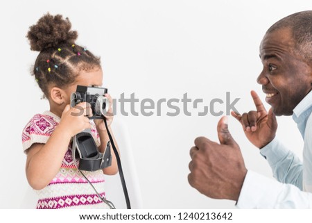Young father with his cute little daughter taking pictures of each other on an old vintage camera