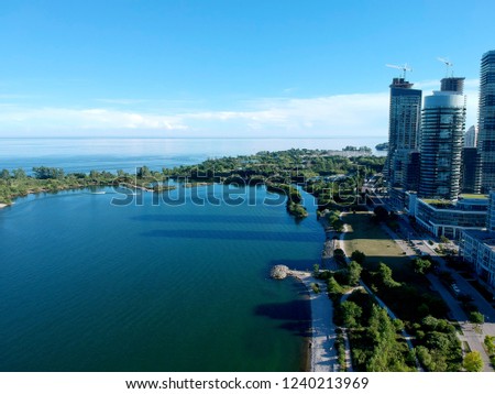 Aerial bird eye shot over Humber Bay Shores Park, Toronto, Canada with coastal condo homes, blue skies, beaches and harbour entrance in view with glass condominiums. Perfect summer day sunset.