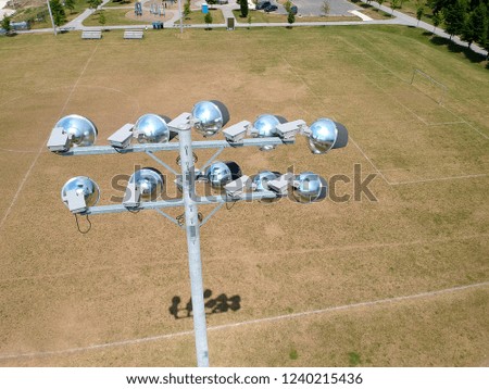 Sports soccer and football with nice green environment, aerial view behind stadium lights or lamps. Recreational activity  ground in top view of field in neighbourhood at sunny hot summer day.