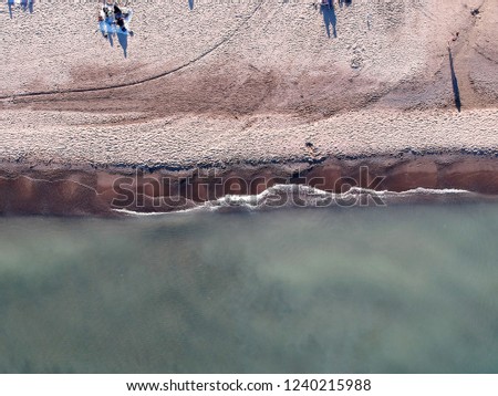 View from above, aerial view of an Mediterranean sea with a white beach and tourists who relax and swim.
