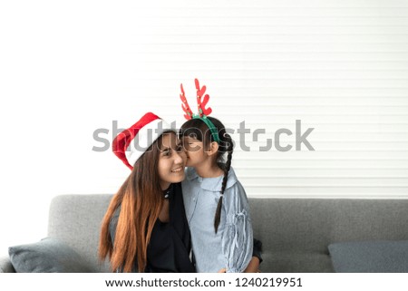Asian mother and daughter happy and kiss together in livingroom at home in christmas day.