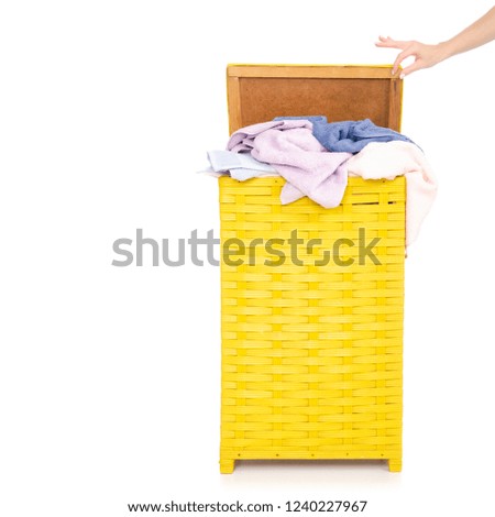 Yellow laundry basket with towels female hand on white background isolation