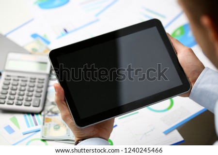 Businessman holds tablet on background of graphs with financial statistics in office. Will study stock market on currency stock exchange concept