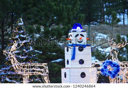 Lighted reindeer and snowman with forest in background