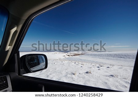 View from the car window to the winter landscape with white snow and blue sky, on a bright sunny day