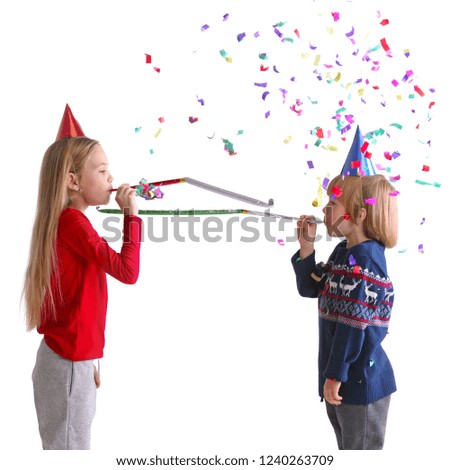 Children blowing party trumpets with confetti celebrating new year