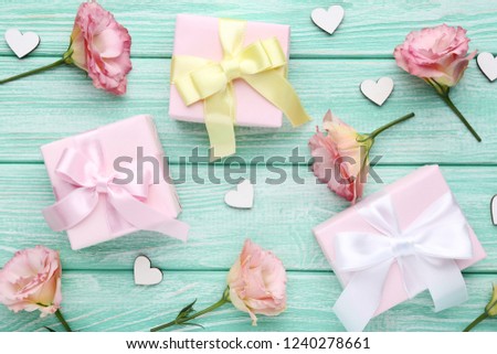 Gift boxes with eustoma flowers and white small hearts on wooden table