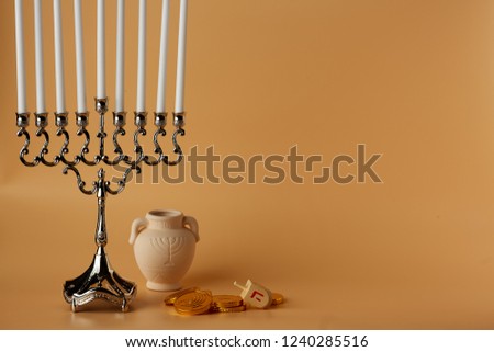 symbols of the Jewish holiday on a peach background, hanukkah, a jar of candles, candies, wooden dreidel