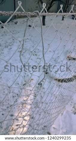Texture and background of an old metal fence or reinforcement against the background of fresh white snow on a clear winter day or morning.