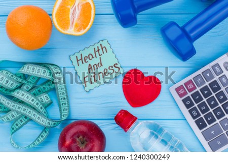 Health and fitness concept. Wooden background with fitness equipment, fruits, measuring tape, calculator and red heart. Diet, weight loss, fitness and health care concept.