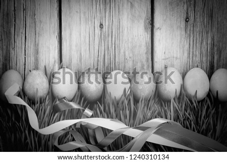Easter eggs in a green grass on a wooden background, authentic Easter decorations. HAPPY EASTER!