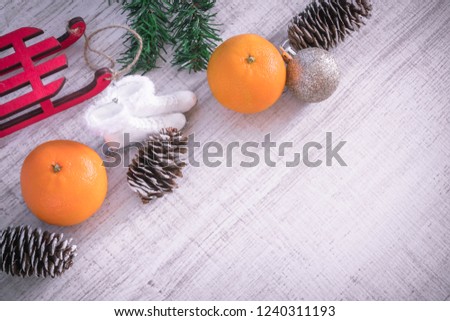 Christmas or New Year composition on a wooden background with red sleds, tangerines and Christmas decorations, pine cones, place for text. holiday composition of the new year. view from above.copy