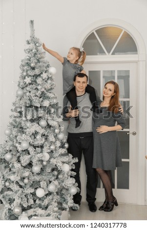 Happy and beautiful family of three at a festive bright New Year's room.