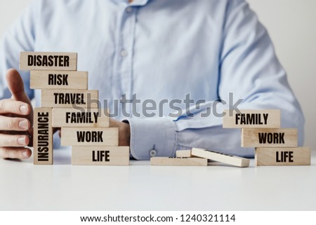 A wooden building supported by a wooden block with the inscription INSURANCE and a destroyed building. Blocks with the words FAMILY, MONEY, RISK. The need for life insurance.