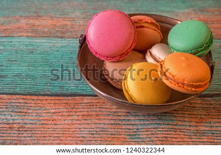 French macarons  in a metal cup on a wooden background.