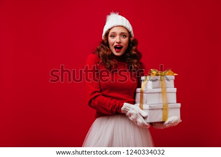 Blissful long-haired ginger woman holding new year gifts. Studio shot of blithesome curly girl celebrating christmas.