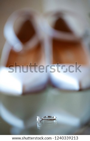 macro photo shooting sleek wedding ring in front of bride shoes