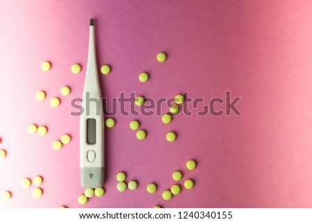 Small medical pharmacetic round pills, vitamins, drugs and electronic digital thermometer on a pink purple background. Concept: medicine, health care, heart disease. Flat lay, top view.