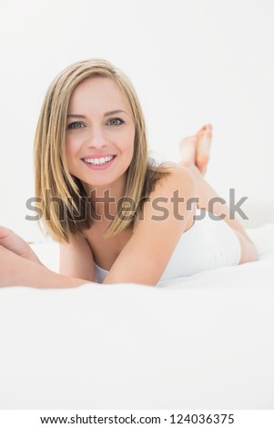 Portrait of beautiful happy young woman lying in bed at home