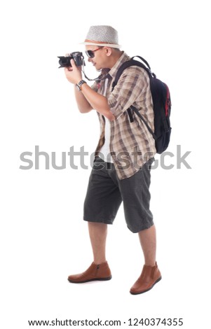 Traveling people concept.Portrait of Asian male backpacker photographer tourist isolated on white. Full body portrait. Taking Pictures with his mirrorrless