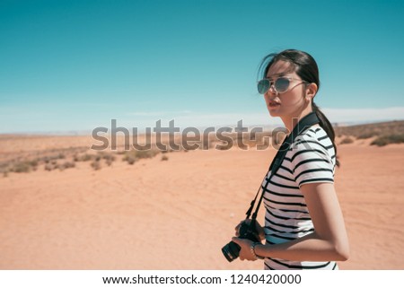 Nature Photographer taking pictures outdoors during hiking trip on grand canyon national park. young lady travel alone to the sand mountain in usa. female with sunglasses standing on desert sunny day
